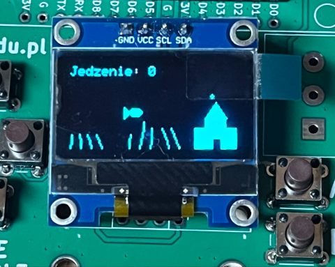 OLED 128x64, napis "Jedzenie: 0", rybka na środku, glony na dole, zamek po prawej, płytka z ESP8266, przyciski do sterowania.